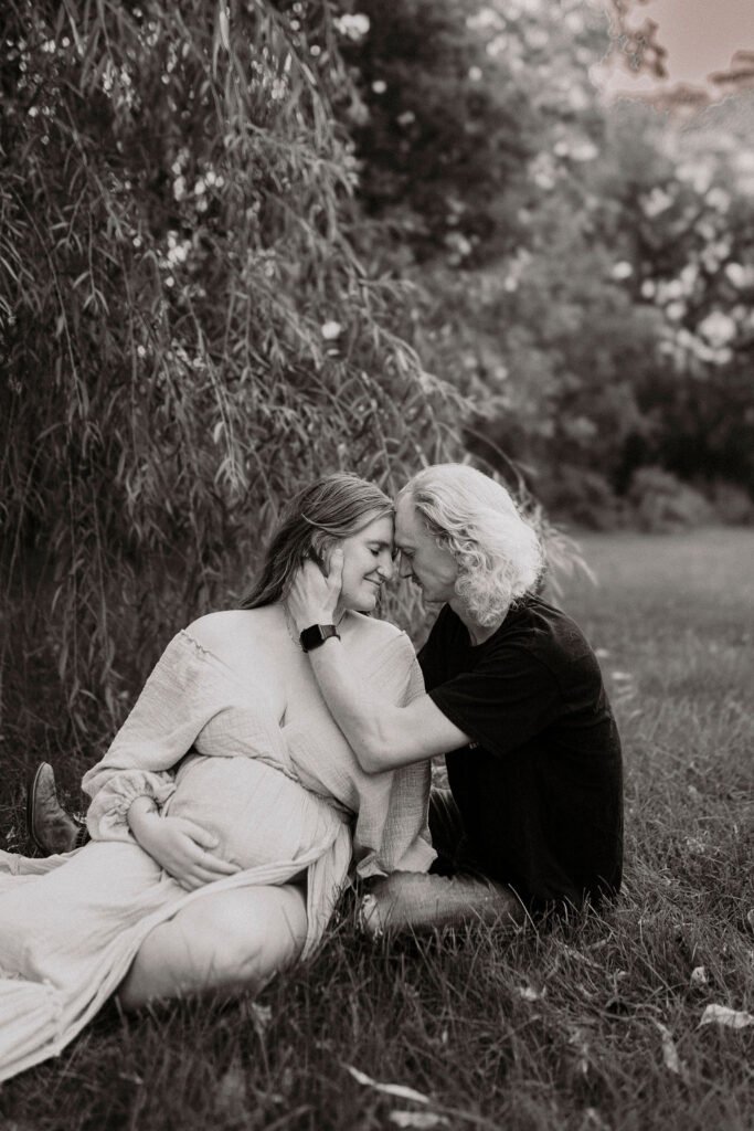 Black and white artistic portrait of pregnant woman under drooping tree branches