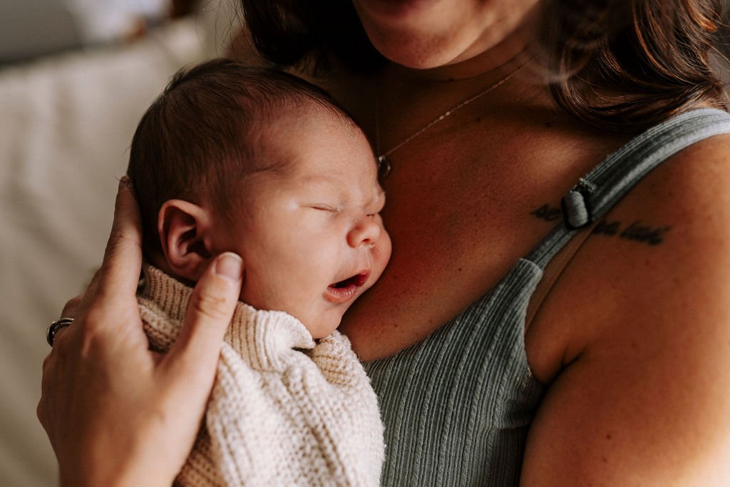 Mother holding sleeping newborn baby during home session