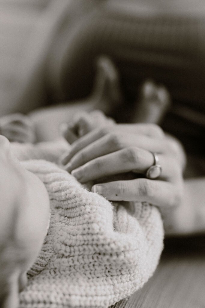 Black and white close-up of newborn baby in knit blanket