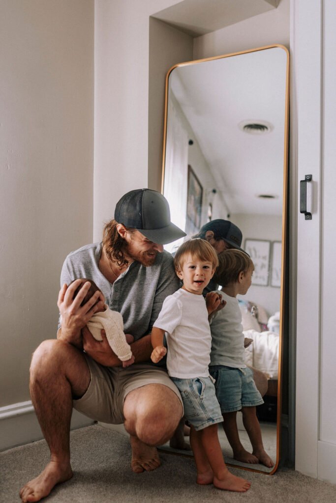 Father with two children sitting in bedroom doorway during family session