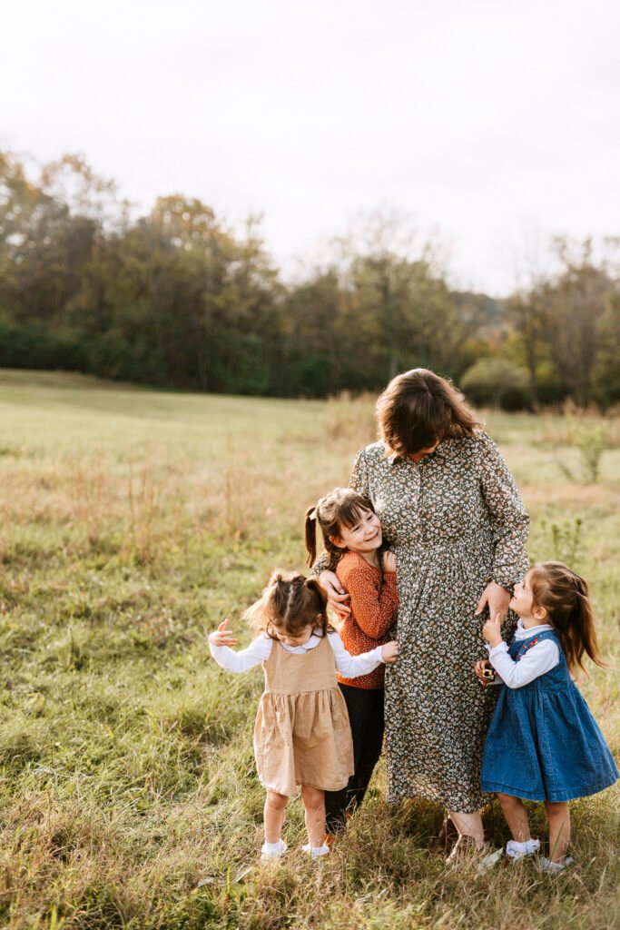 Mom standing in field with three daughters during family pictures in Franklin