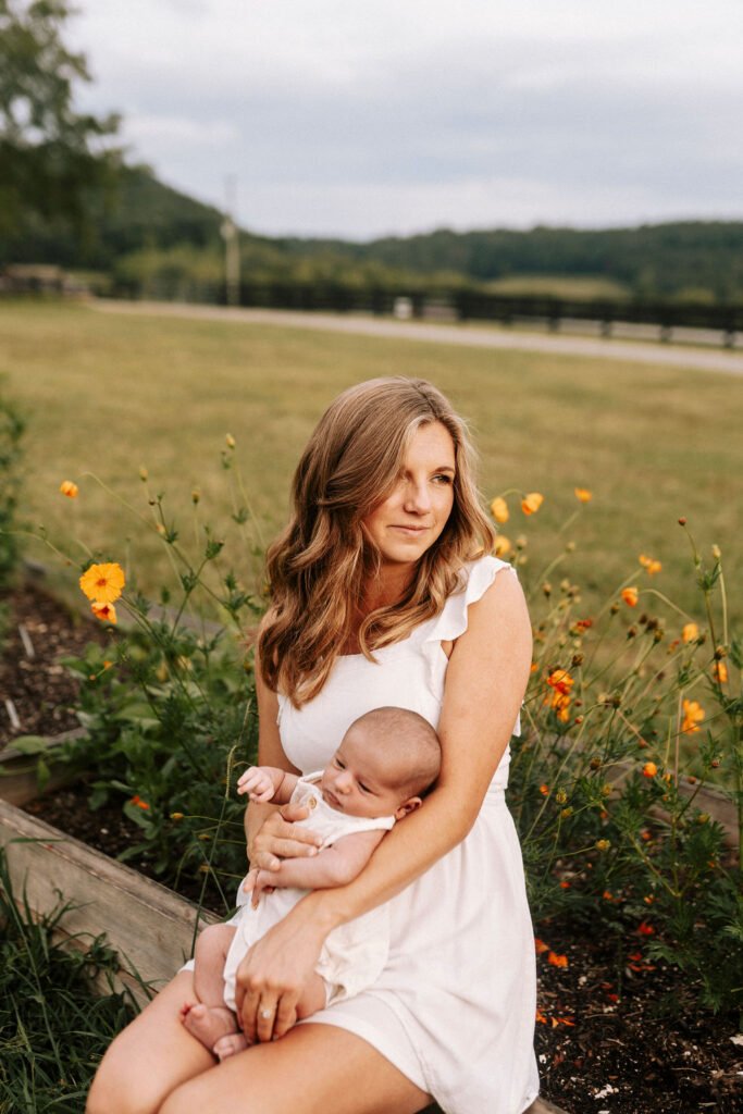 Mom holding her baby while outside in her flower garden