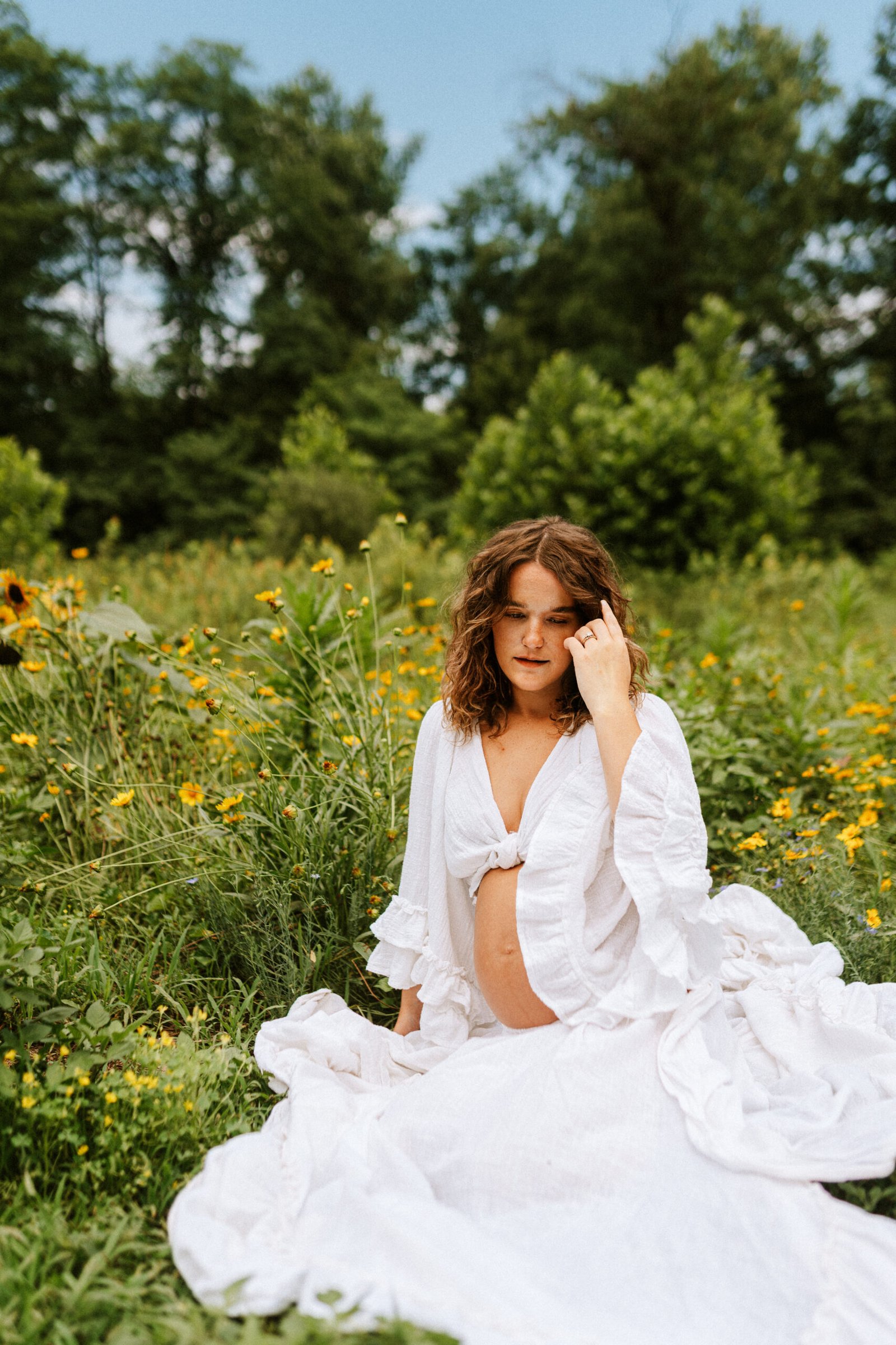Mom sitting in flower field during maternity pictures