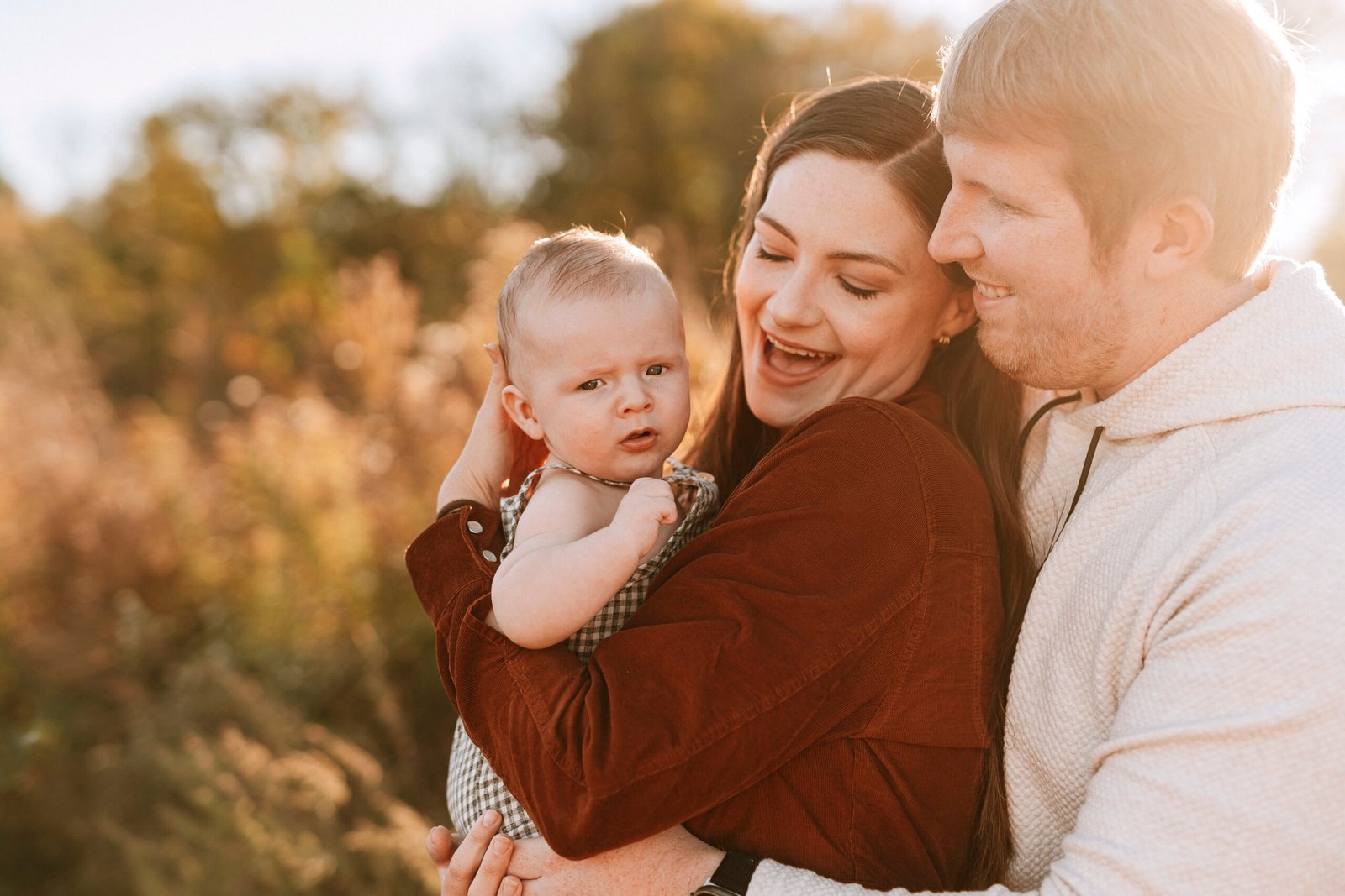 Mom and dad holding their baby close at golden hour during fall family pictures
